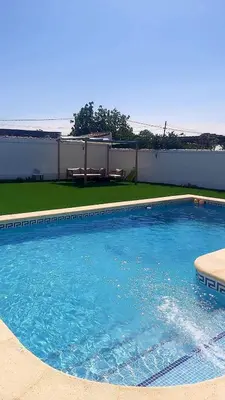 a swimming pool with blue water in front of a building at Chalet Vacacional Chiclana in Chiclana de la Frontera