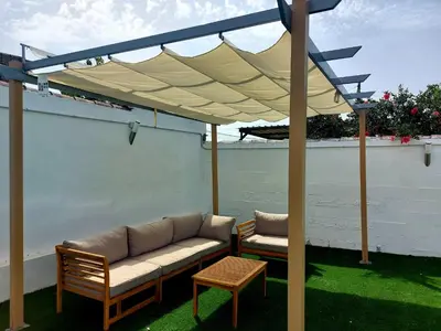 a patio with a couch and two chairs under a canopy at Chalet Vacacional Chiclana in Chiclana de la Frontera