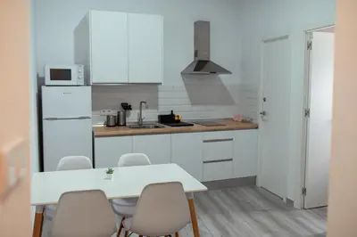 a kitchen with white cabinets and a table and chairs at APARTAMENTO EL EMBRUJO in Jerez de la Frontera