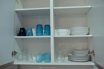 a white cabinet filled with plates and bowls and glasses at APARTAMENTO EL EMBRUJO in Jerez de la Frontera