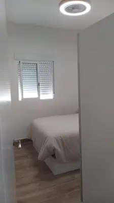 a white bedroom with a bed and a window at Casa Ángeles in Cádiz