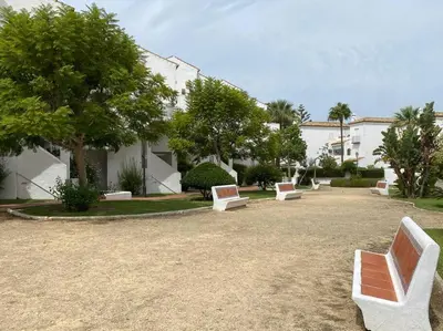 a group of white benches sitting in a park at Cozy Apart. Costa Sancti Petri by Chiclana Dreams in Novo Sancti Petri