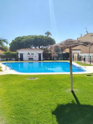 a large swimming pool with an umbrella in a yard at Apartamento Costa de Sancti Petri by Chiclana Dreams in Novo Sancti Petri