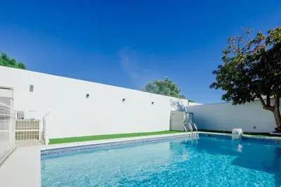 a swimming pool in front of a white wall at Moon Villa Conil con piscina in Conil de la Frontera