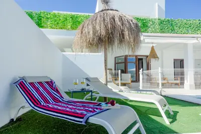 a group of chairs and an umbrella on a yard at Moon Villa Conil con piscina in Conil de la Frontera