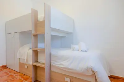 a bedroom with a bunk bed with white sheets at Moon Villa Conil con piscina in Conil de la Frontera