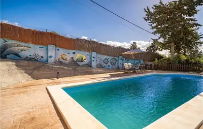 a swimming pool in front of a wall with a mural at Lovely Home In Chiclana De La Fronter in Chiclana de la Frontera