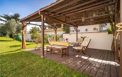 a wooden deck with a table and chairs under a pergola at Lovely Home In Chiclana De La Fronter in Chiclana de la Frontera