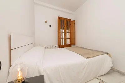a white bedroom with a bed and a window at Vegaluz in Jerez de la Frontera