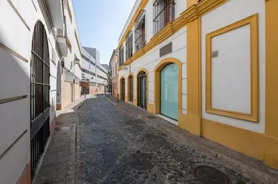 an empty street with yellow and white buildings at Vegaluz in Jerez de la Frontera