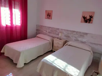 two beds in a bedroom with red curtains at Casa Caleta in Conil de la Frontera