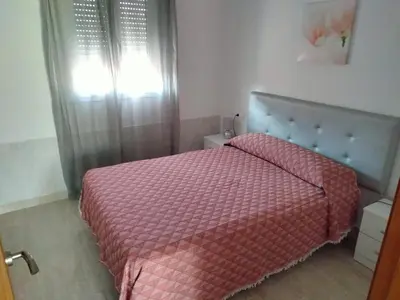 a bedroom with a bed with a red comforter and a window at Casa Caleta in Conil de la Frontera