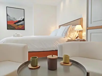 a bedroom with a large bed and two white chairs at Casita de la Suerte in Medina Sidonia