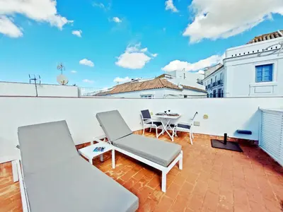a patio with a table and chairs on a roof at Casita de la Suerte in Medina Sidonia
