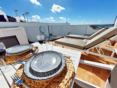 a table with plates and wine glasses on a balcony at Casita de la Suerte in Medina Sidonia