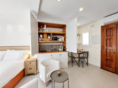 a bedroom with a bed and a table and a kitchen at Casita de la Suerte in Medina Sidonia