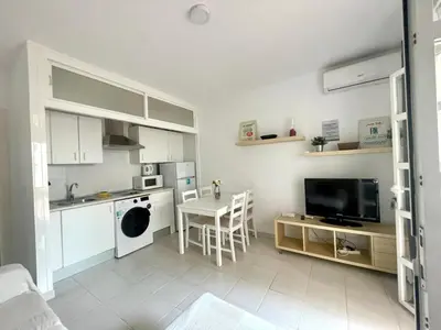 a living room with a kitchen and a table with chairs at Pescadores del Sur in Chiclana de la Frontera