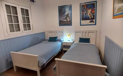 two beds in a bedroom with posters on the wall at Casa Victoria in Arcos de la Frontera