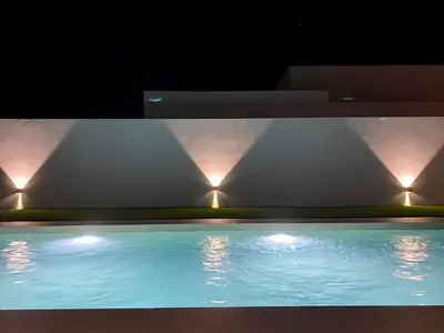 a swimming pool with lights on the side of a building at Villa Tres Mares in Novo Sancti Petri