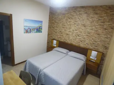 a bedroom with a bed and a brick wall at Hostal Campo Nuevo in Sanlúcar de Barrameda