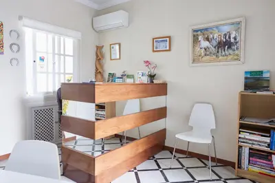 a living room with a book shelf and two chairs at Hostal Campo Nuevo in Sanlúcar de Barrameda