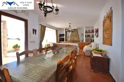 a dining room and living room with a table and chairs at Chalet con Piscina privada en Conil in Conil de la Frontera