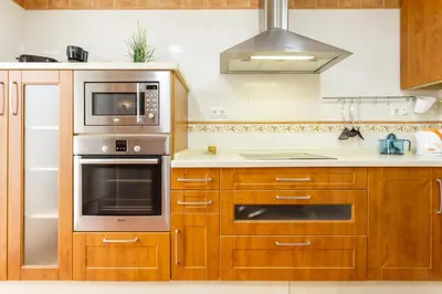 a kitchen with wooden cabinets and stainless steel appliances at Apartamento con patio en Cádiz centro in Cádiz