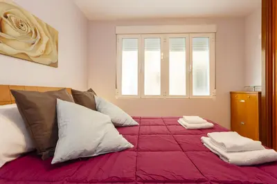 a bedroom with a large bed with red sheets and pillows at Apartamento con patio en Cádiz centro in Cádiz