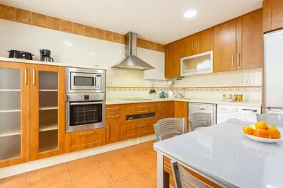 a kitchen with wooden cabinets and white appliances at Apartamento con patio en Cádiz centro in Cádiz