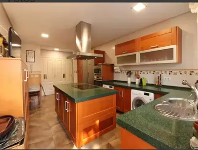 a kitchen with wooden cabinets and a green counter top at Villa Sagrario in Chiclana de la Frontera