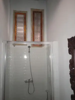 a shower with a hose in a bathroom with two windows at La gota de leche 3 in Sanlúcar de Barrameda