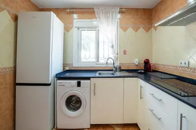 a kitchen with a white refrigerator and a washing machine at El Verano Azul Casa con piscina in Chiclana de la Frontera