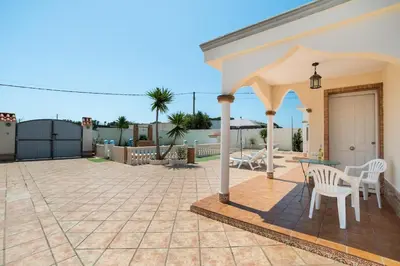 a patio with a table and chairs on it at El Verano Azul Casa con piscina in Chiclana de la Frontera