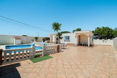 a house with a fence and a swimming pool at El Verano Azul Casa con piscina in Chiclana de la Frontera