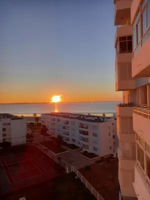 a sunset over a city with buildings and a tennis court at Primera línea Valdelagrana in El Puerto de Santa María