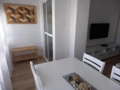 a dining room with a white table and a television at Primera línea Valdelagrana in El Puerto de Santa María