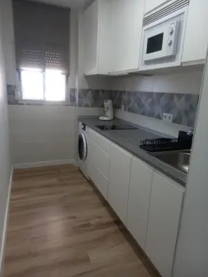 a kitchen with white cabinets and a sink and a microwave at Primera línea Valdelagrana in El Puerto de Santa María