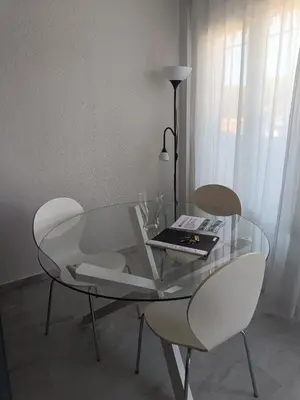 a glass table with two chairs and a book on it at Apartamento Red de Almadraba in Chiclana de la Frontera