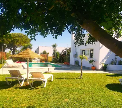 a yard with two chairs and an umbrella and a swimming pool at Olas de Conil in Conil de la Frontera