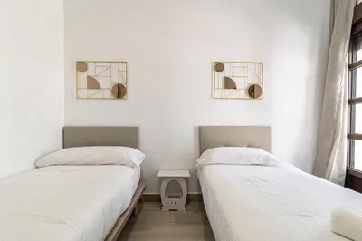 two beds in a room with white walls at Allo Apartments Arroyo Catedral in Jerez de la Frontera