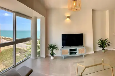 a living room with a flat screen tv and large windows at Espectacular apartamento frente al mar in El Puerto de Santa María