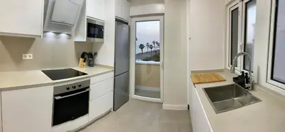 a kitchen with white cabinets and a sink and a window at Espectacular apartamento frente al mar in El Puerto de Santa María