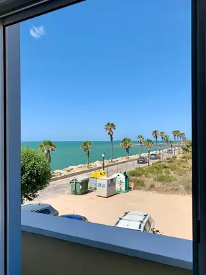 a view of a parking lot with palm trees and the ocean at Espectacular apartamento frente al mar in El Puerto de Santa María