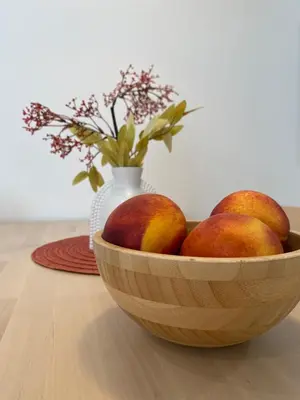 a wooden bowl of peaches on a table with a vase at ARCO apartamento junto a la Catedral de Cádiz in Cádiz