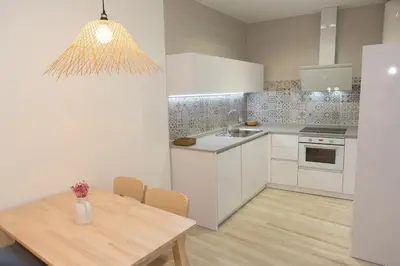 a kitchen with white cabinets and a wooden table at ARCO apartamento junto a la Catedral de Cádiz in Cádiz