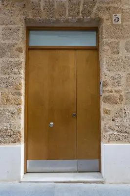 a brown door in a brick wall at ARCO apartamento junto a la Catedral de Cádiz in Cádiz