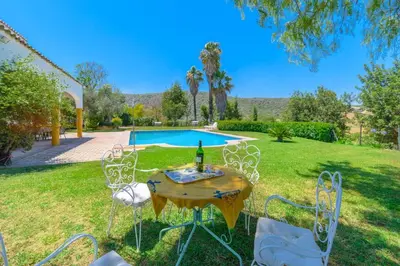 a table with a bottle of wine on it in a yard at Private Villa Cortijo Sierra y Lago with private swimming pool in Arcos de la Frontera