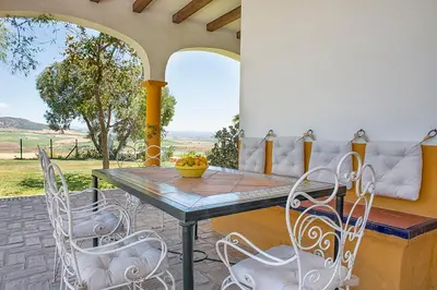 a patio with a table and chairs and a couch at Private Villa Cortijo Sierra y Lago with private swimming pool in Arcos de la Frontera