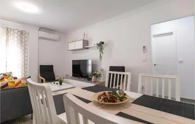 a dining room and living room with a table and chairs at Cozy Apartment In Sanlúcar De Barrameda in Sanlúcar de Barrameda