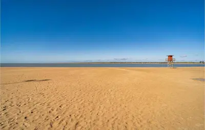 a beach with a lifeguard tower in the middle of the sand at Cozy Apartment In Sanlúcar De Barrameda in Sanlúcar de Barrameda